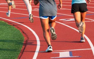 Visió per darrere d'uns nois i noies corrent en una pista d'atletisme