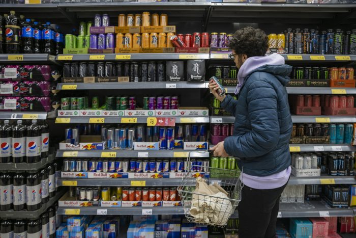 Jove en un supermercat davant la secció de les begudes de cafeïna