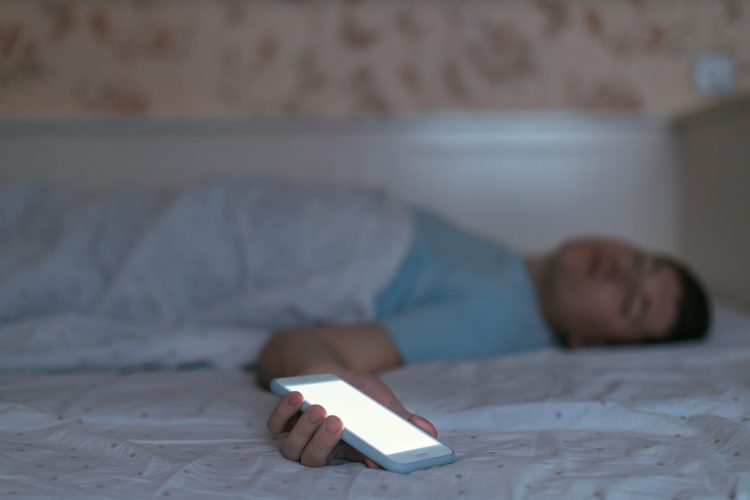 Adolescent adormit amb el mòbil a la mà
