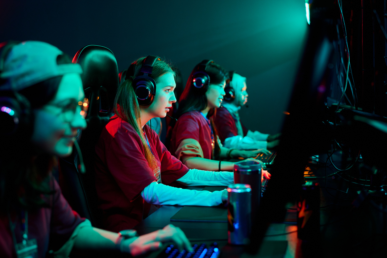 Grupo de mujeres jovenes jugando a videojuegos en linea con auriculares en un entorno competitivo