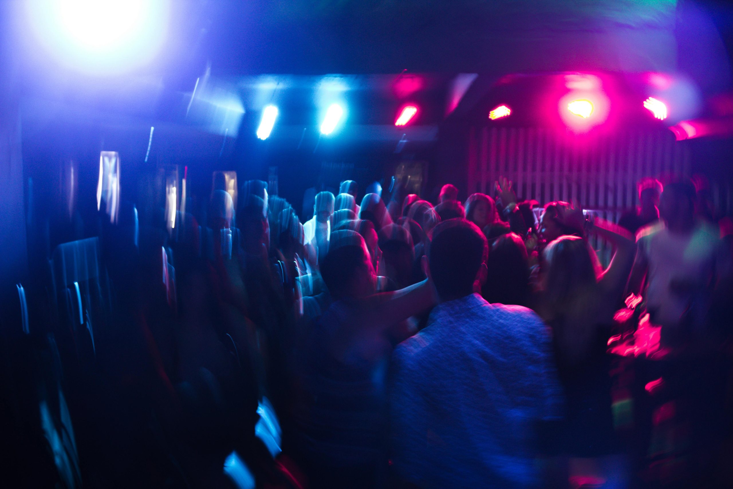 persones ballant en una discoteca amb llums de colors representant els efectes estimulants inicials de l’alcohol i la desinhibició